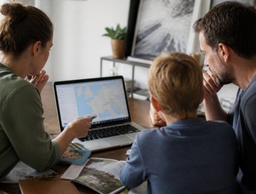 Gezin dat aan een vakantietafel reisopties vergelijkt op een laptop en reisgidsen bekijkt