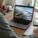Persoon met checklist voor het vergelijken van vakanties op een laptop en notitieboekje
