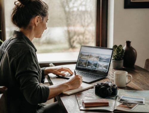 Iemand vergelijkt vakanties op laptop en noteert voorwaarden aan tafel